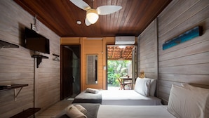 A room with wooden walls, a ceiling fan, a bed with white linens, a small table, and a bench with towels. - Pousada Treze Luas (Paranaguá)