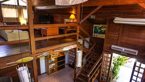 A multi-level wooden cabin with a TV, bookshelves, a staircase, and a map on the wall. - Pousada Treze Luas (Paranaguá)