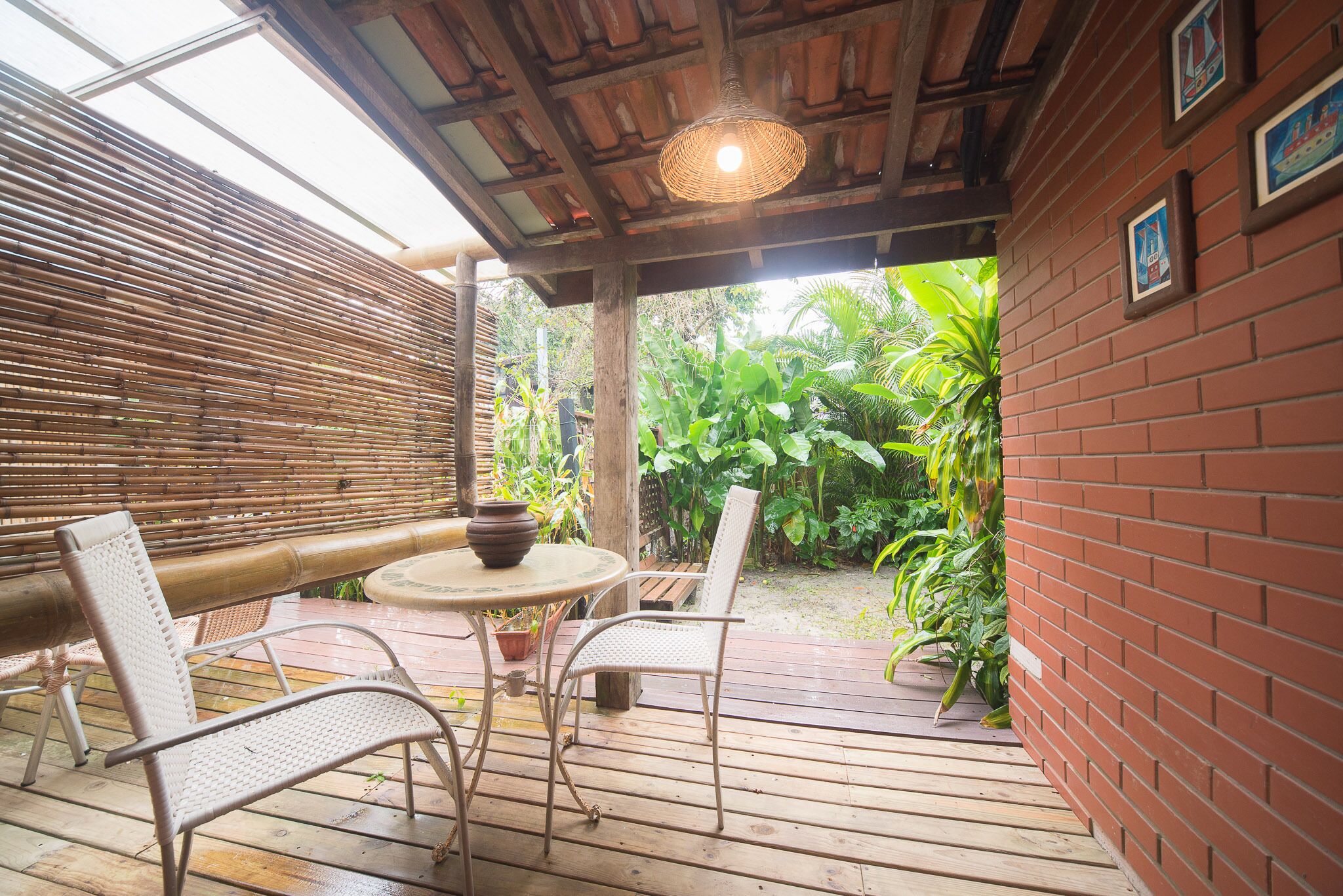 A covered patio with a bamboo wall, a round table, and two chairs.