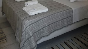 Ein Hotelzimmer mit Bett, Nachttisch, Lampe und einem Fenster mit Vorhängen.