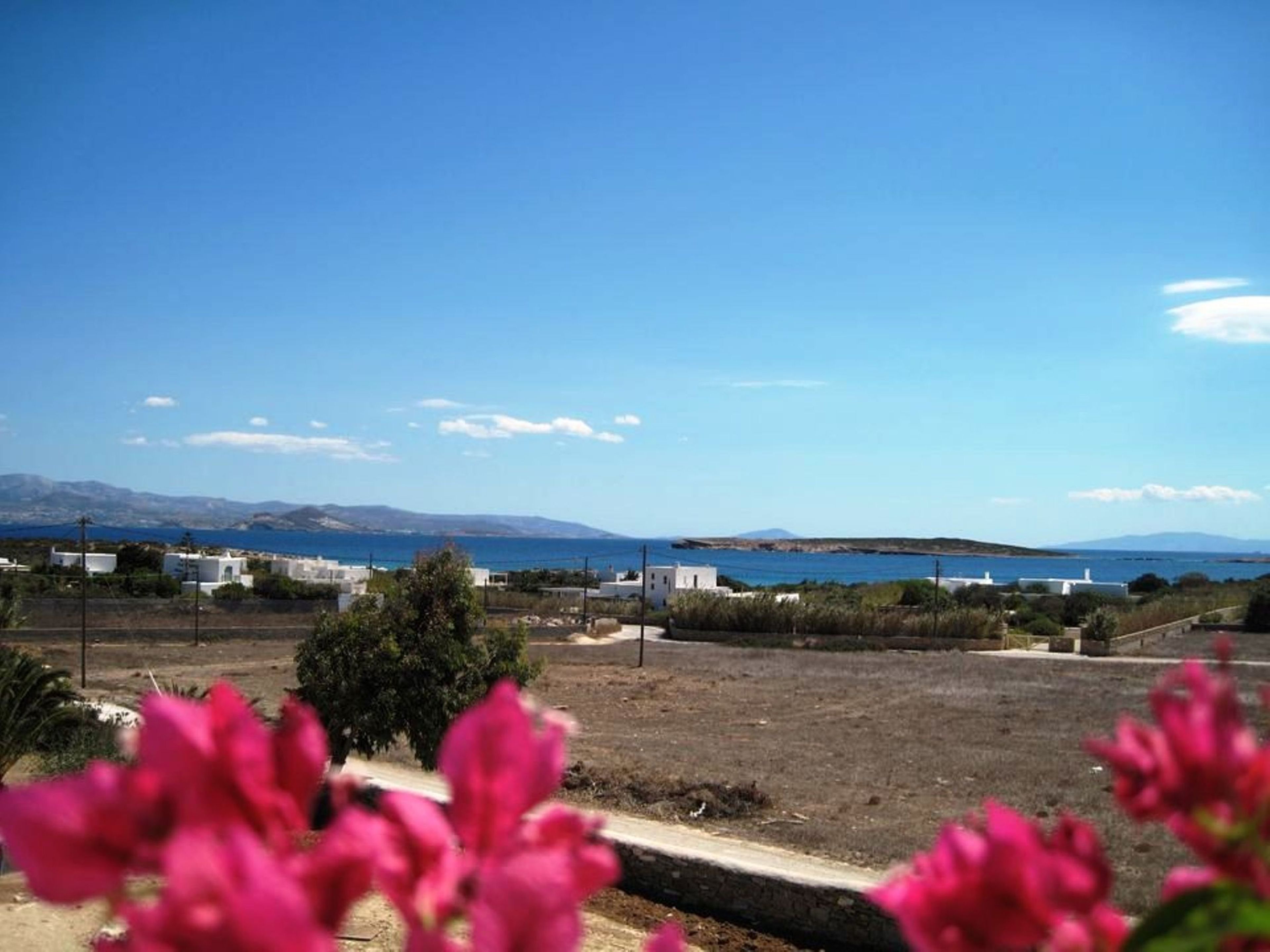 A coastal landscape with white buildings, a clear blue sky, and distant mountains.
