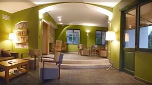Een gezellige woonkamer met een bank, fauteuils, een salontafel en een boekenkast.