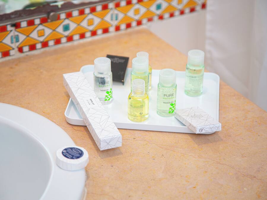 Una encimera de baño con artículos de aseo y una botella de gel de ducha.