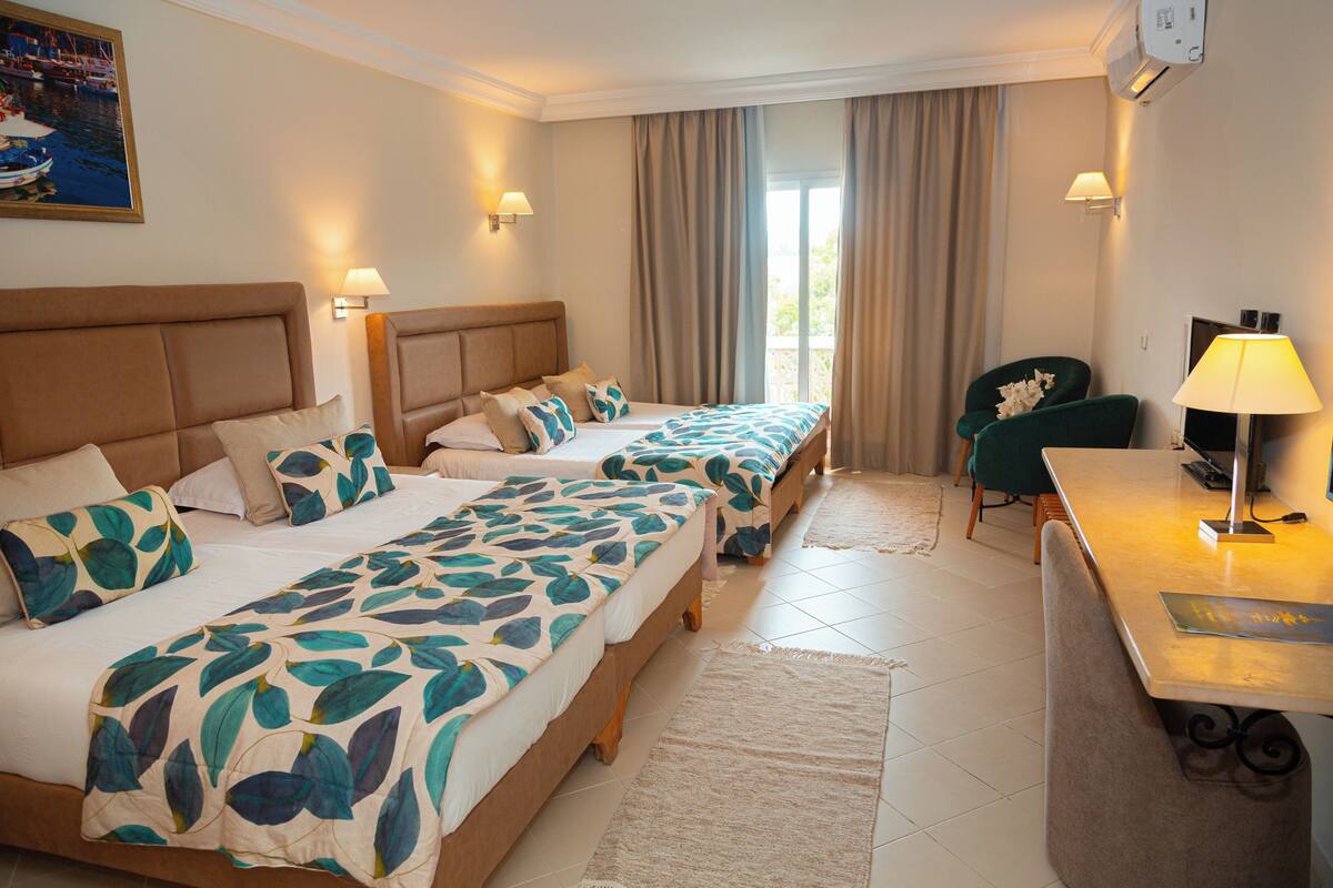 A hotel room with two beds, a desk, and a chair.