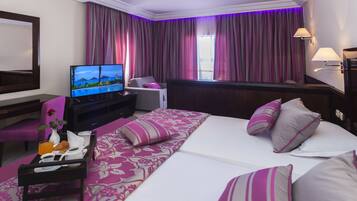 Habitación de hotel con cama, televisión, escritorio y bandeja de desayuno, además de una ventana con cortinas.