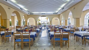 A spacious dining hall with multiple tables and chairs, large windows, and a view of the outdoors. - Itropika Hôtel (Tabarka)