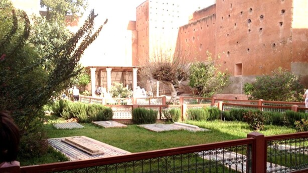 A courtyard with a fountain, neatly trimmed hedges, and a brick wall. - Arabian Riad (Marrakech)