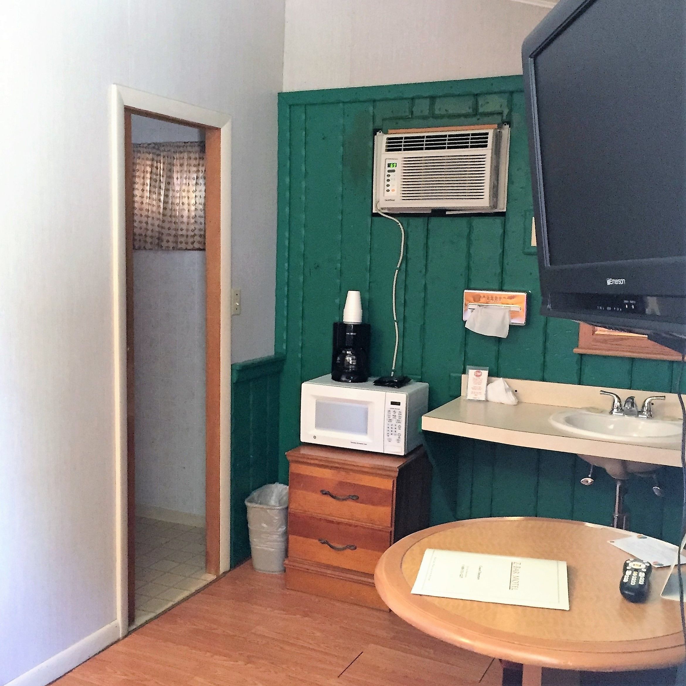 Une petite pièce, de taille réduite, équipée d’un four à micro-ondes, d’un évier et d’un téléviseur.