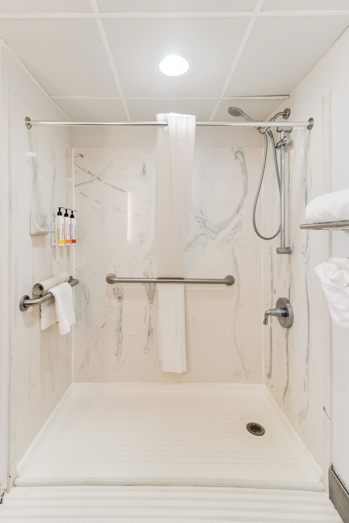A walk-in shower with a glass door, a towel rack, a hand dryer, and a showerhead.