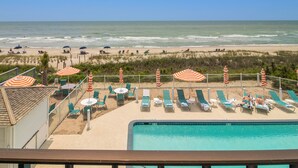 A beachside pool area with lounge chairs and umbrellas, overlooking the ocean. - Crystal Coast Oceanfront Hotel (Atlantic Beach)