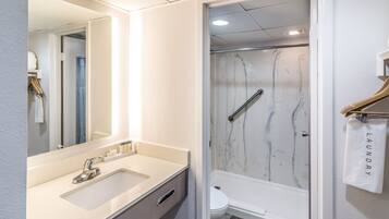 A modern bathroom with a marble shower, a white sink, and a toilet.