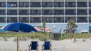 A beachfront hotel with multiple balconies, beach chairs, and umbrellas. - Crystal Coast Oceanfront Hotel (Atlantic Beach)
