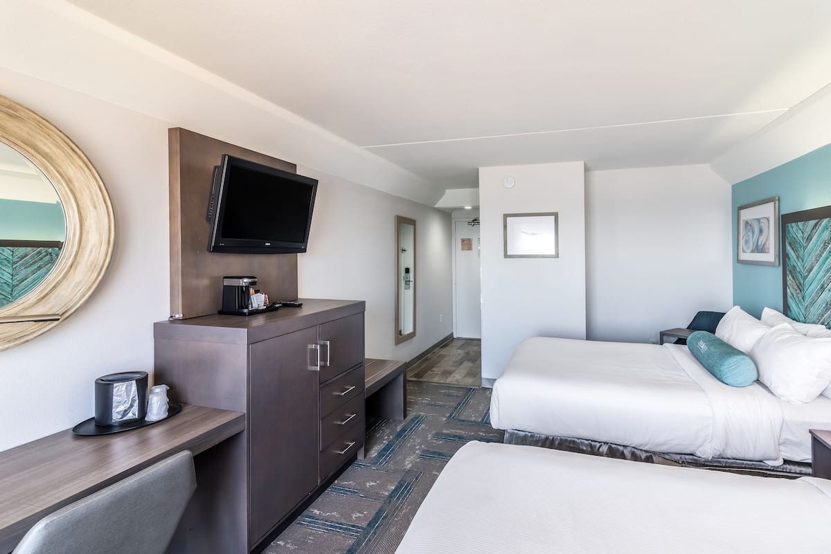 Ein Hotelzimmer mit Bett, Schreibtisch mit Kaffeemaschine, Fernseher und Spiegel.