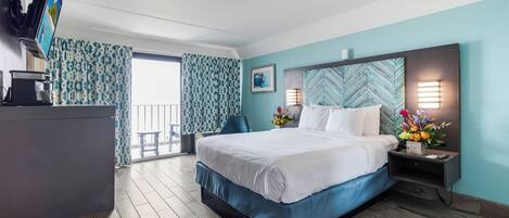A hotel room with a bed, a desk, a TV, a nightstand, and a window with curtains.