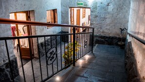 A stone-floored corridor with a metal railing, a door labeled 'SALIDA', and a small plant. - El Portal de San Lázaro (Arequipa)