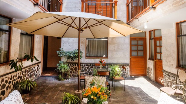 A courtyard with a central table, two sofas, and a large umbrella. - El Portal de San Lázaro (Arequipa)