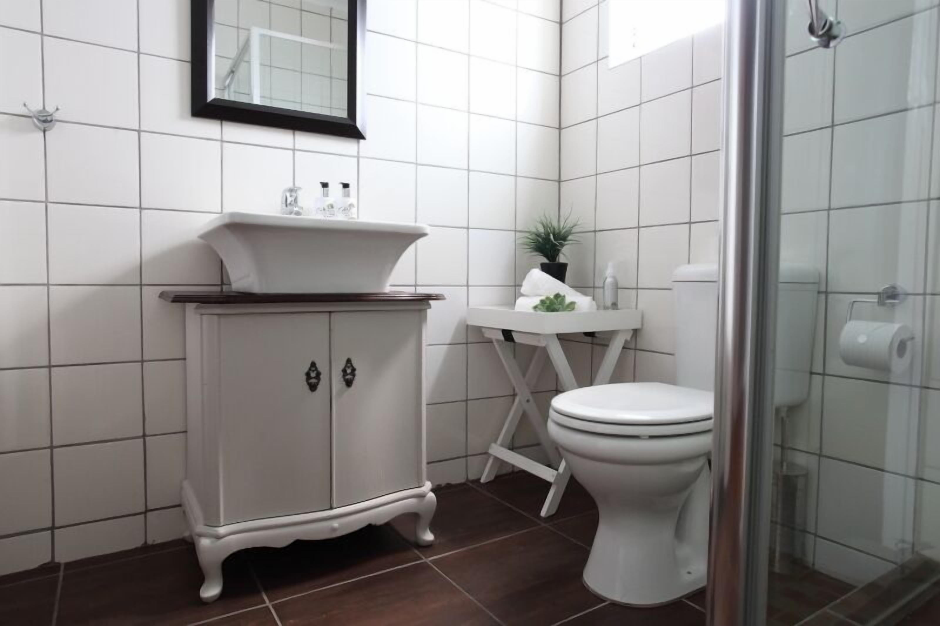 Une salle de bain avec un lavabo, un meuble et des toilettes, le tout de couleur blanche.