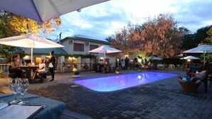 An outdoor patio area with a swimming pool, tables, and umbrellas. - Celtis Country Lodge and Restaurant (Inxuba Yethemba)