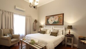 A bedroom with a large bed, a chair, a bedside table, a lamp, and a painting on the wall. - Celtis Country Lodge and Restaurant (Inxuba Yethemba)