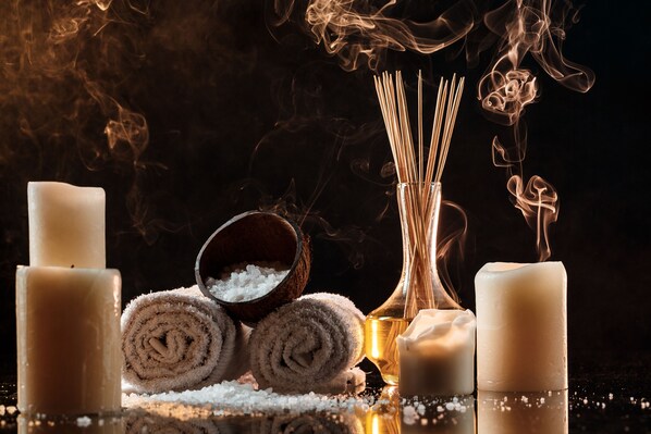 Un ambiente de spa con velas, toallas enrolladas y un bol de sal.