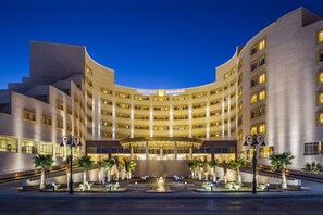 Een hotel met meerdere verdiepingen, een gebogen gevel, een centraal atrium en een fontein in de binnenplaats.