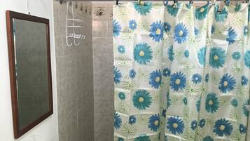 A bathroom with a shower curtain featuring a floral pattern, a sink with a soap dispenser, and a mirror on the wall.