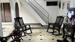 Un vestíbulo con piso de baldosas, una escalera y varias sillas de mecedora de madera.