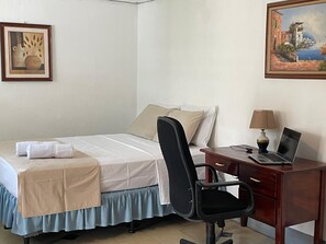 A bedroom with a bed, a desk with a laptop, a chair, and a painting on the wall. - El Callejon Guest House (León)