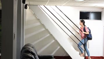 Una persona baja una escalera en un edificio con un sofá negro y un televisor montado en la pared.