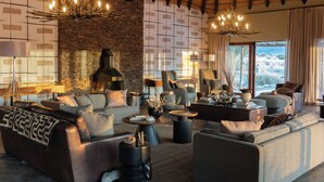 Un salon spacieux doté d’une cheminée en pierre, de canapés en cuir et de luminaires modernes.