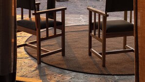 Une chaise et une table en bois, placées sous une zone abritée, offrent une vue sur un paysage désertique.