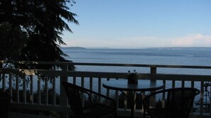A balcony with a table and chairs overlooking a body of water. - Skiff Point Guest House (Bainbridge Island)
