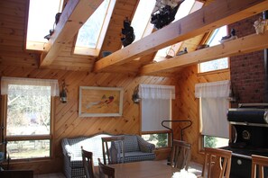 Un chalet confortable avec une chambre à coucher en mezzanine, un coin repas et une cuisine équipée d’un barbecue.