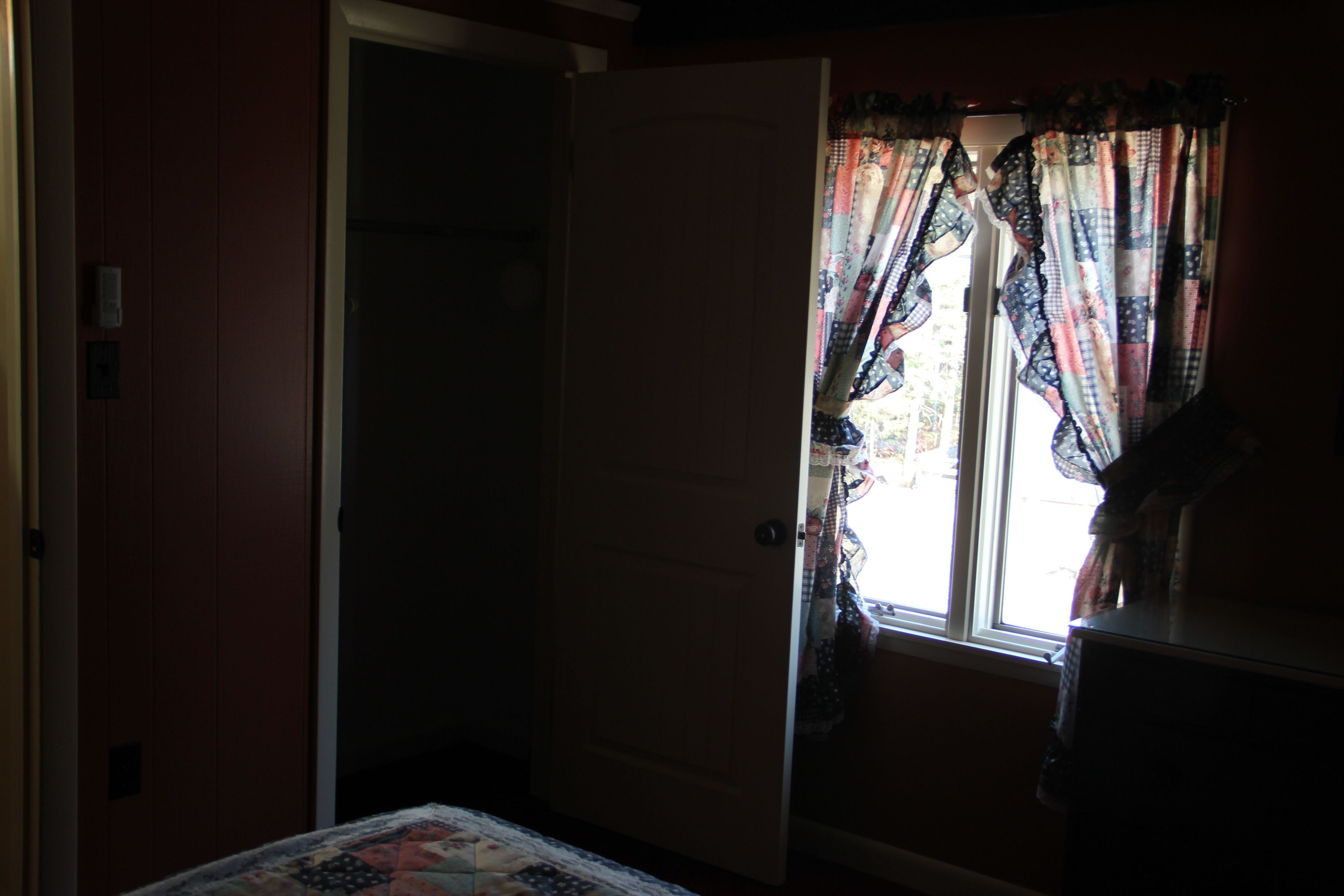 A room with a bed, a door, and a window with curtains.