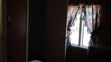 A room with a bed, a door, and a window with curtains.