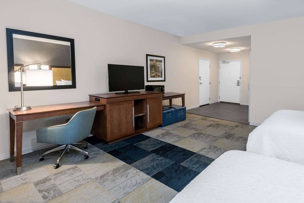 Une chambre d’hôtel équipée d’un bureau, d’une chaise, d’une télévision et d’un lit.