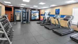Une salle de sport équipée de tapis de course, d’haltères et d’appareils de musculation.