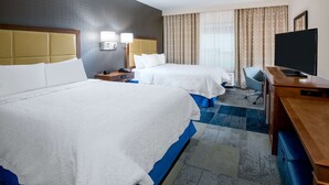 Une chambre d’hôtel avec deux lits, un bureau, une télévision et une chaise.