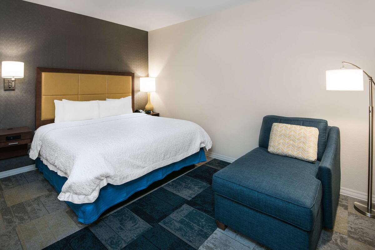 Une chambre d’hôtel avec un lit, une table de chevet, une lampe et une chaise.