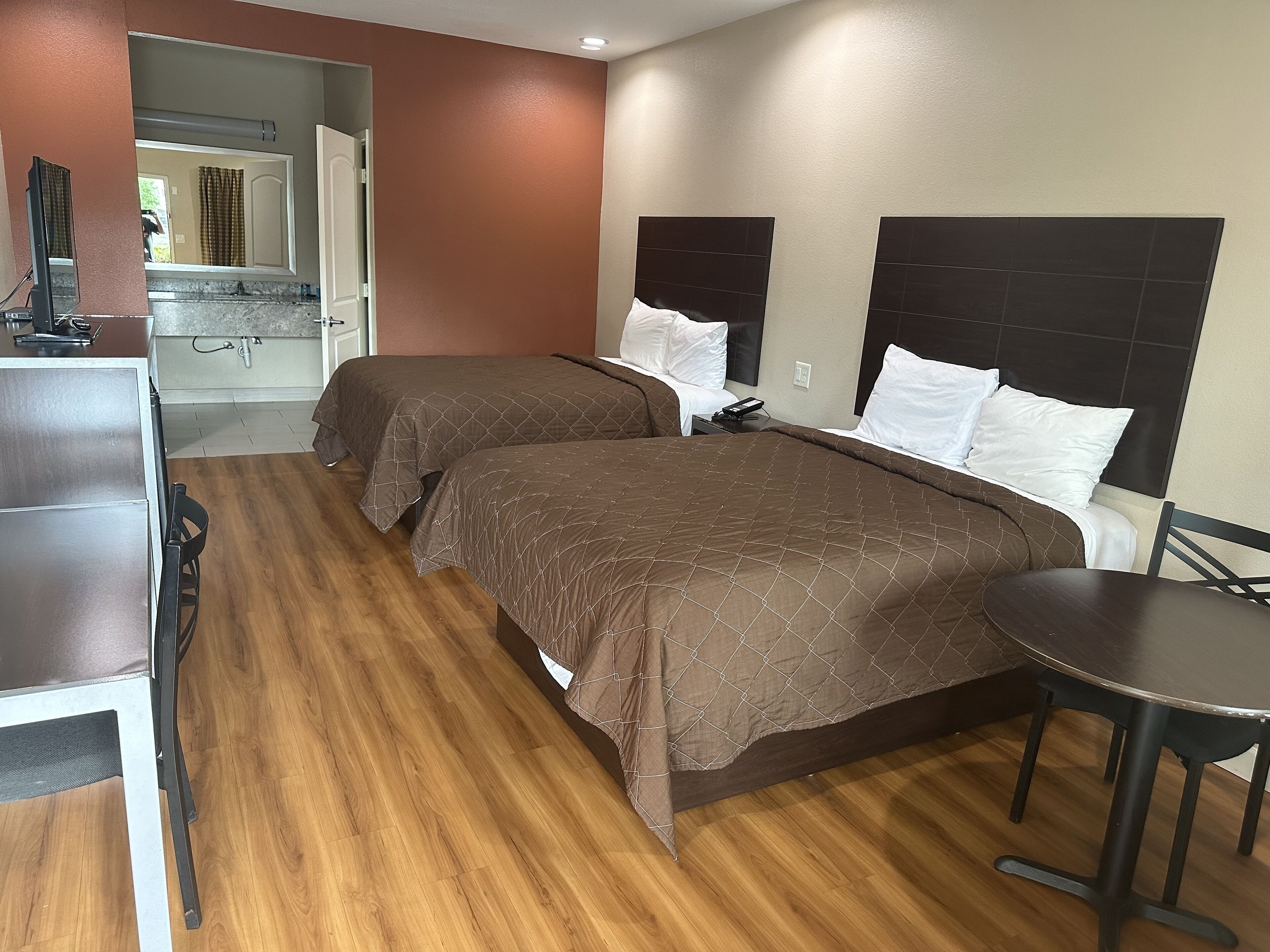 A hotel room with two beds, a desk, and a chair.