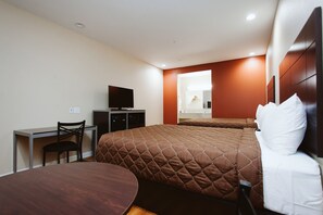 A hotel room with a bed, a desk, a chair, a television, and a mirror.