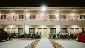 A multi-story hotel with a central walkway, two parking spaces, and a red car parked on the right. - Palace Inn 290 & Jones Rd (Houston)