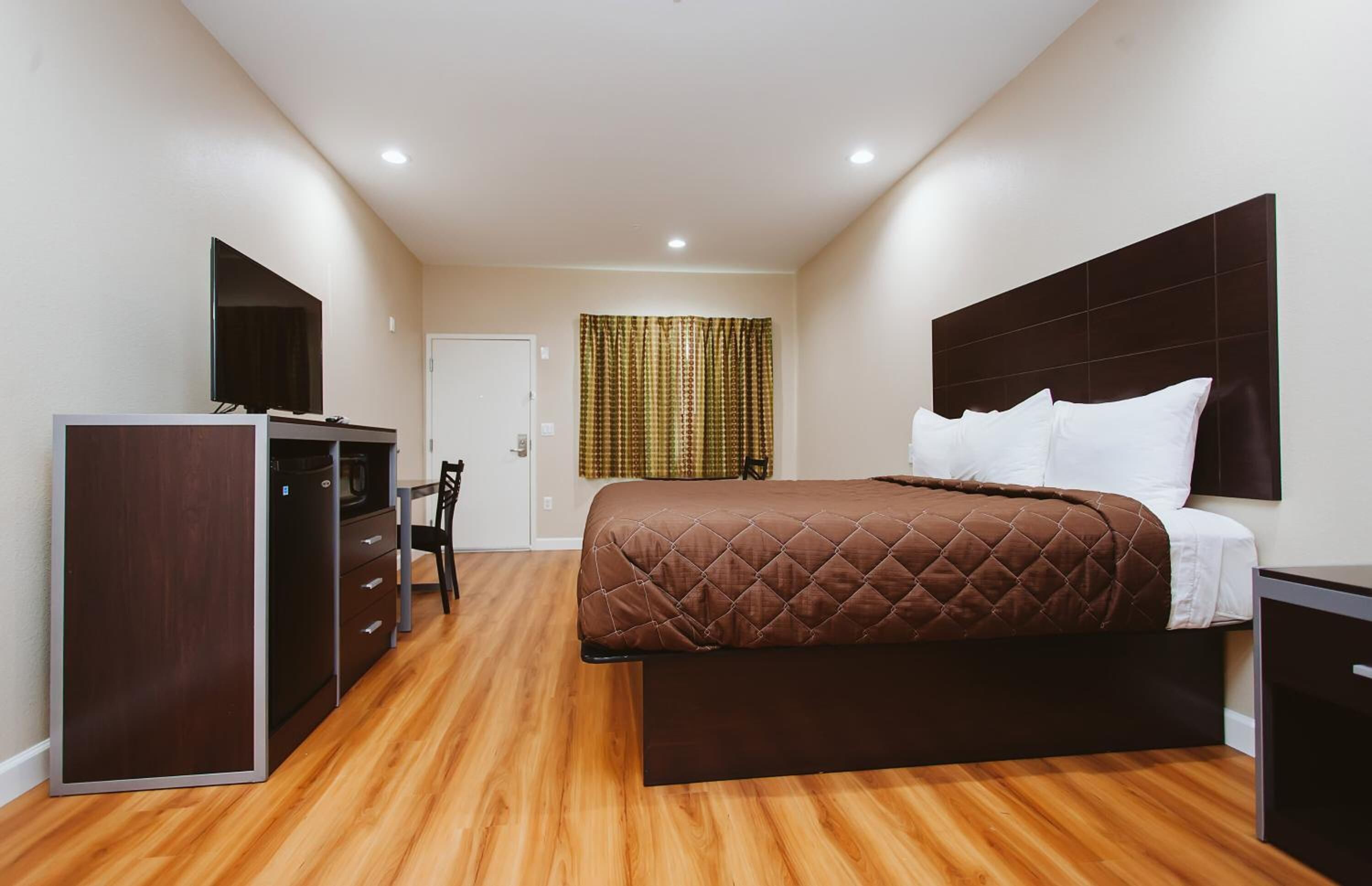 Una habitación de hotel con una cama, un escritorio, una silla y un televisor.