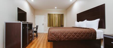 Una habitación de hotel con una cama, un escritorio, una silla y un televisor.