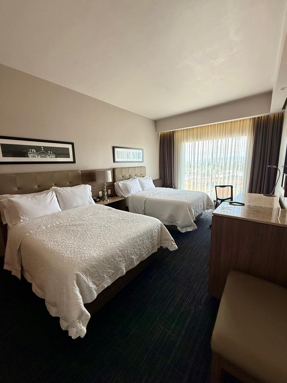 Ett hotellrum med två sängar, ett skrivbord och en stol.