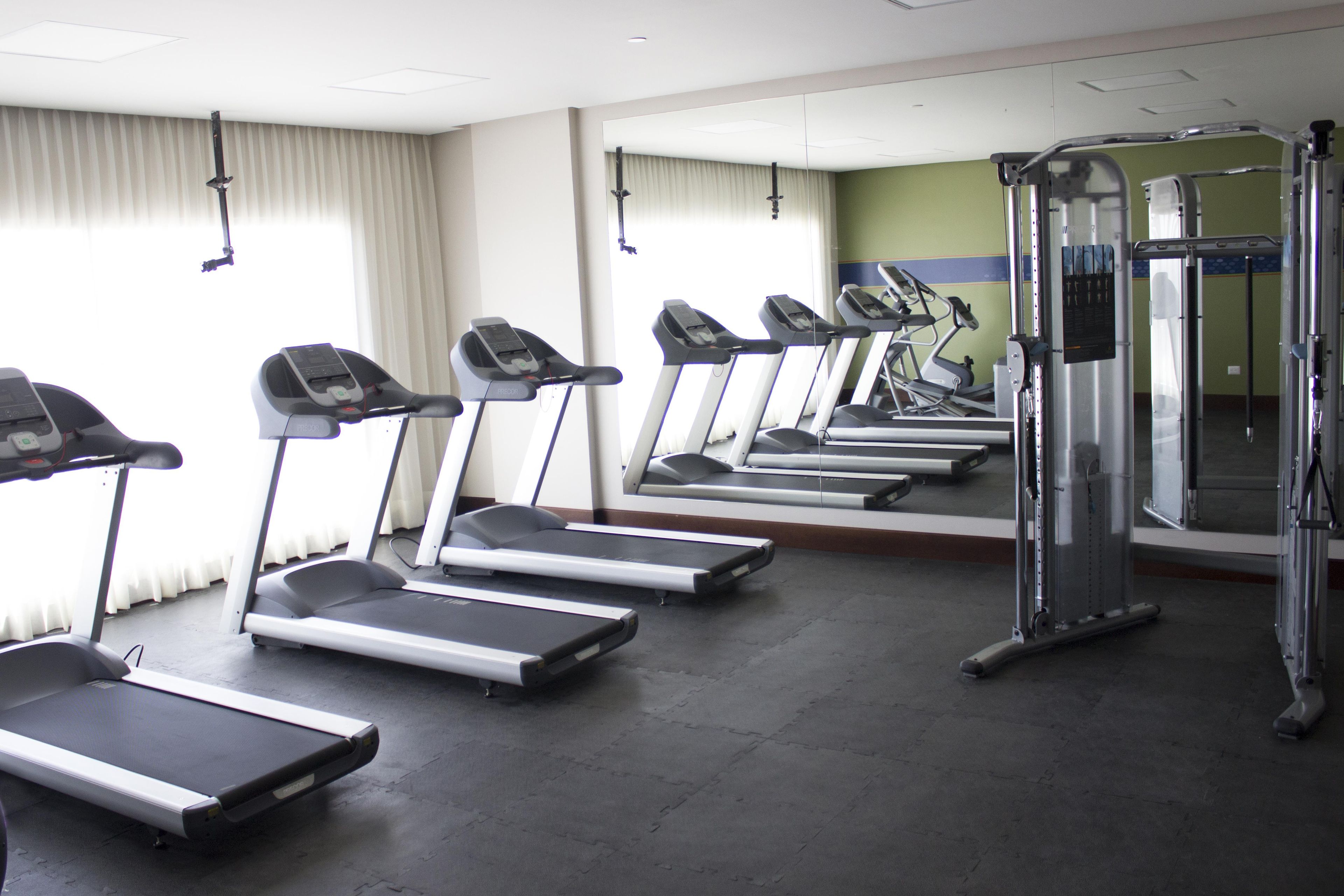 A gym with multiple treadmills, a mirrored wall, and a weight machine.