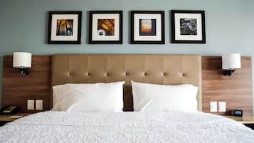 A hotel room with a large bed, two bedside lamps, and four framed pictures on the wall.