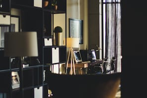 A modern office space with a desk, computer, and chair. There is a bookshelf with various items and a window with curtains. - Hampton Inn by Hilton Durango (Durango)