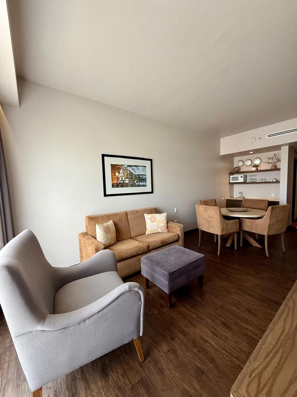 Una sala moderna con sofá, sillón, reposapiés y comedor con sillas y una mesa.