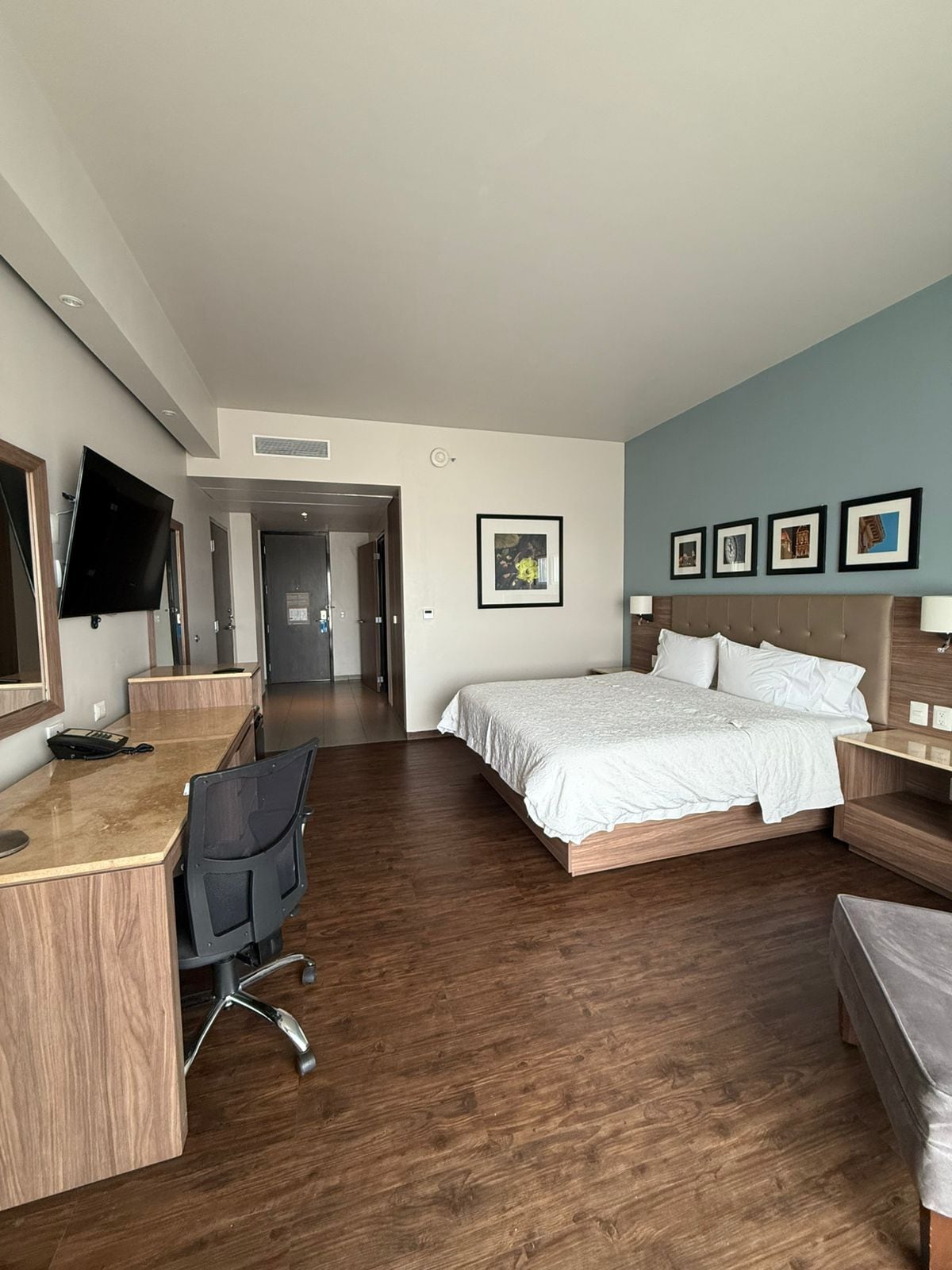 A hotel room with a bed, desk, chair, and a television.